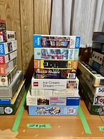 Stack of 8 puzzle boxes showing brands and piece counts including Ravensburger, Cobble Hill, Buffalo, LEGO, and others.