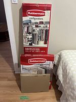 The three boxes of the Rubbermaid Configurations 610 closet system, showing the sealed packaging with product images and labeling.
