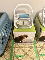 SureFeed feeder atop its retail box showing removable two-compartment bowl and instruction pamphlet