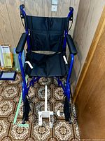 Front view of blue Medline transport wheelchair with white Formedica grab bar on floor