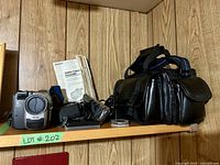 Sony CCD-TRV53 camcorder and all original accessories on wood shelf including battery charger, strap, manual, and carrying case.