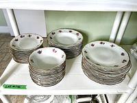 Full set of stacked dishes including dinner plates, soup bowls, salad bowls, and dessert plates on two shelves.