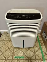 Front view of the white Whirlpool dehumidifier showing digital control panel, air intake grill and water level window.