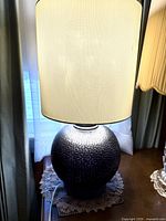 Modern hammered metal base lamp with large cream fabric shade from front in natural lighting