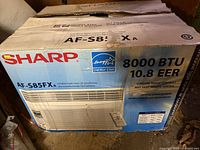 Original boxed Sharp AF-S85FXA window air conditioner showing front of box with brand, model, and specifications.