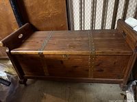 Photo of the full cedar hope chest showing wood grain, metal strap hinges, side handles, and overall shape.