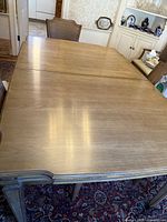 View of the solid wood dining table with two leaves extended, showing the smooth wood surface and custom protective pads.