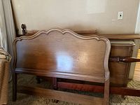 Full size bed frame headboard and part of bureau seen behind bed