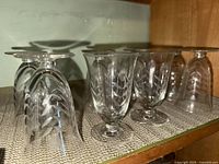 Four stemmed cocktail glasses showing clear glass with cut etched leaf and shell patterns.