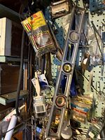 Photo of pegboard with hanging hand tools including large metal spirit levels, clamps, and packages of hardware items.