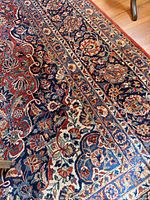 Close-up of the red Persian Saruk style rug showing intricate floral patterns and border design on wood floor.