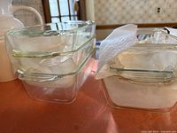 Stack of 4 clear vintage Pyrex glass baking dishes in varying sizes showing glass handles and thickness