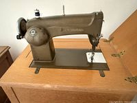 Side view of vintage Black Swanhouse sewing machine on flat surface.