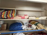 Shows various folded blankets including a colorful crocheted afghan, blue wool blanket and Snoopy blanket