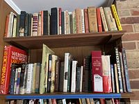 Wide view showing two shelves filled with various books, including Webster's dictionary and National Geographic Magazine.