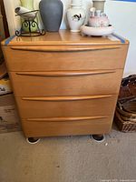 Front view showing four drawers with integrated handles and light wood finish.