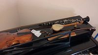 Buffet clarinet, violin with bow, small guitar with bow on black surface