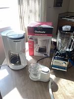 Full view of all three appliances on table with coffee maker box and kitchen background