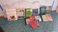 Entire lot of 11 books including cookbooks, gardening, health, and organizing books arranged on the floor.