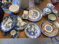 Wide view of all items including floral plates, Bareuther plate, trinket dish with dragon, Smithsonian plates, and lidded cups and bowls