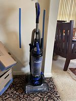 Front full view of the upright Eureka vacuum cleaner showing handle, hose, and main unit on carpet.