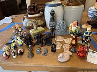 Overall shot of collection showing a wide range of figurines including monkeys, children, stone and ceramic pieces on a table.