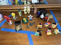 Wide view of all items arranged on wooden table, showing assortment of bird figurines, Asian children figurines, vases, carved wooden pieces, and trinket boxes