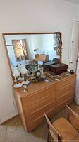 Full view of wooden dresser with mirror and items on top, showing style and condition.