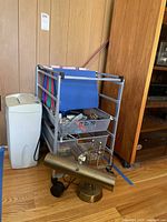 Two-drawer metal cart with hanging files, paper shredder next to it, brass desk lamp and small office items arranged in front.
