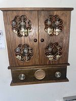 Closed wooden spice rack with metal decorative grilles on doors, radio speaker, and two knobs below