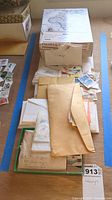 Overall view of boxes and envelopes containing various stamps on a wooden floor surface