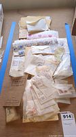 Overview photo of envelopes, sheets, and loose stamps laid on a flat surface showing a collection of various postage stamps and related packaging.