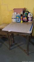 Full view of the vintage rectangular dinner table with cleaning bottles on top showing table legs and condition.