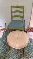 Front view of green wooden chair with blue seat cushion and white vinyl ottoman in front