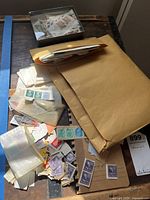 Overview of large quantity of vintage stamps in envelopes, paper, and small glassine sleeves.