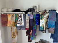 Full view of scarves hanging on a rod including two hats and gloves on top shelf with vintage change bag underneath.