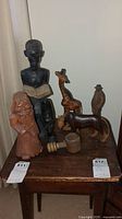 Wood figurines including human bust reading a book, giraffe, horse, bird, and other human figure on a small wooden table