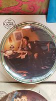 Close-up photo of a decorative plate featuring a boy reading by lamplight, marked with Edwin M. Knowles branding.