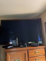 Full view of Panasonic 50-inch flat screen TV on wooden cabinet with remote and 3D glasses visible