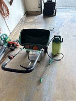 Photo showing Scotts Deluxe EdgeGuard seed spreader and Melnor garden sprayer together on garage floor.