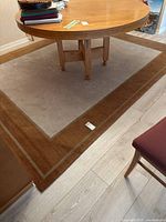 Overall view of rectangular rug under table, shows beige center and brown border.