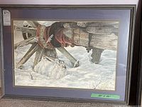 Full view of the framed print showing the embroidered rabbit under a wooden wagon wheel with a red band, surrounded by snow and dry grass, with size label 35x25 inches.