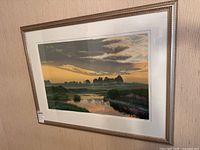 Framed landscape art print hanging on wall showing full image and frame.