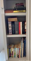 Bookshelf with assorted books including several Bibles and religious texts