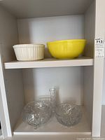 Upper shelf with white ceramic ribbed bowl and large yellow ceramic bowl