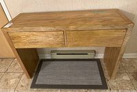 Front view of wooden table showing both drawers and base against wall on tile floor