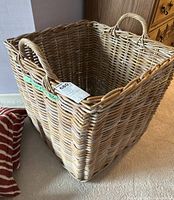 Front angle view of the wicker laundry basket, showing woven texture and handle on the side.