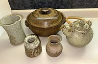 Overview of all 5 pottery pieces on a countertop including casserole, teapot, pitcher and two vases, showing size and glaze pattern
