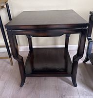 Front view of solid wood side table showing curved legs and lower shelf