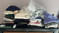Full view of stacked women's clothing in various colors with clear plastic hangers on top